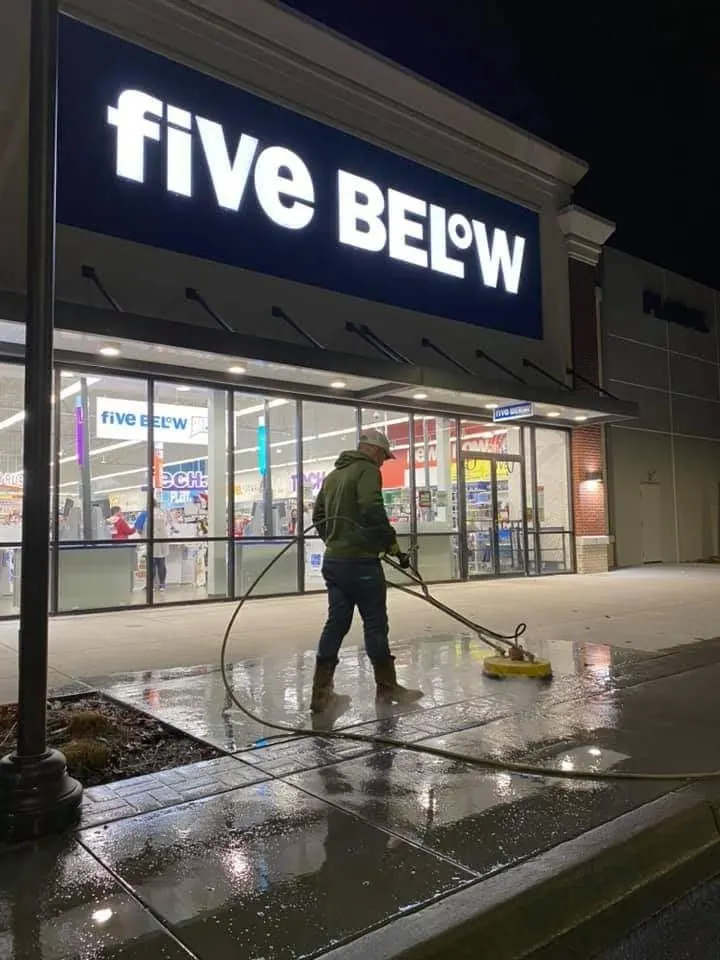 Surface cleaning the sidewalk in front of a retail store at night