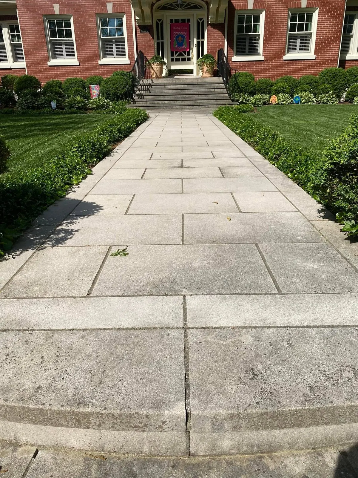 Long paver walkway leading to the front steps of a red-brick home