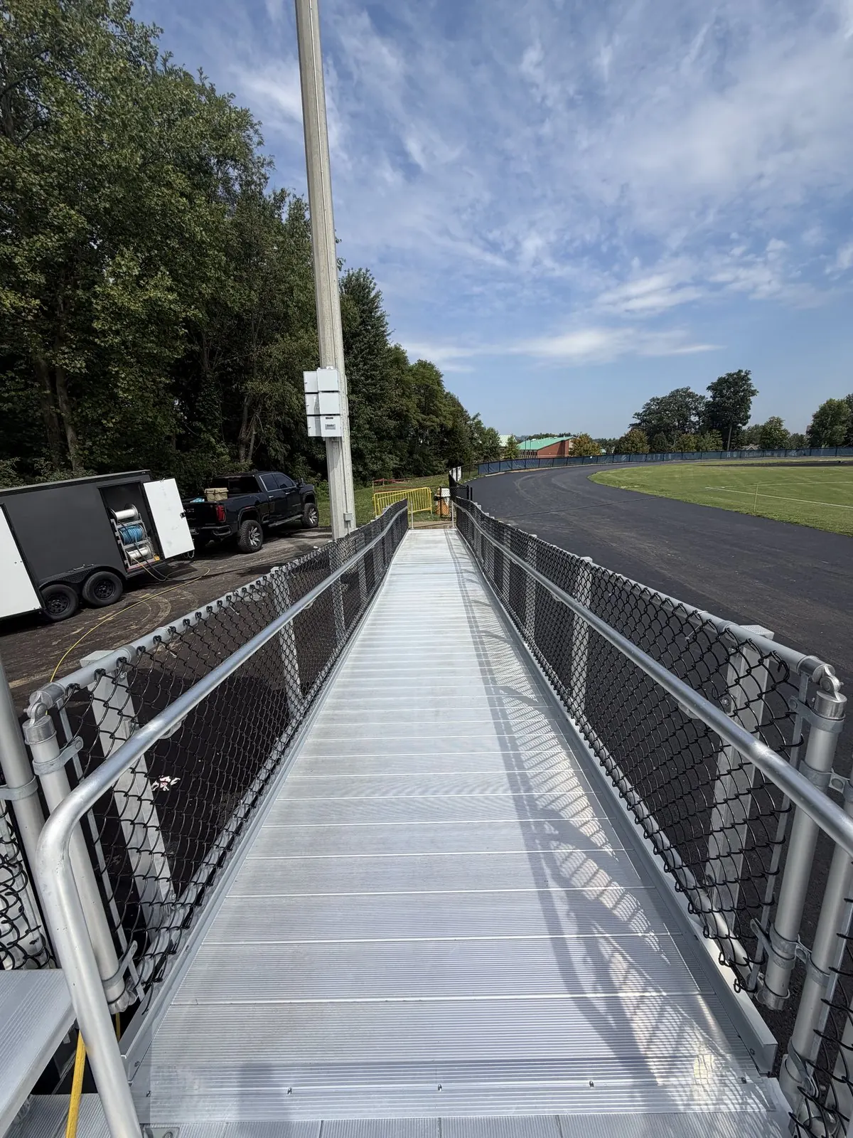 Aluminum stadium ramp with an equipment trailer and a pickup truck parked beside it