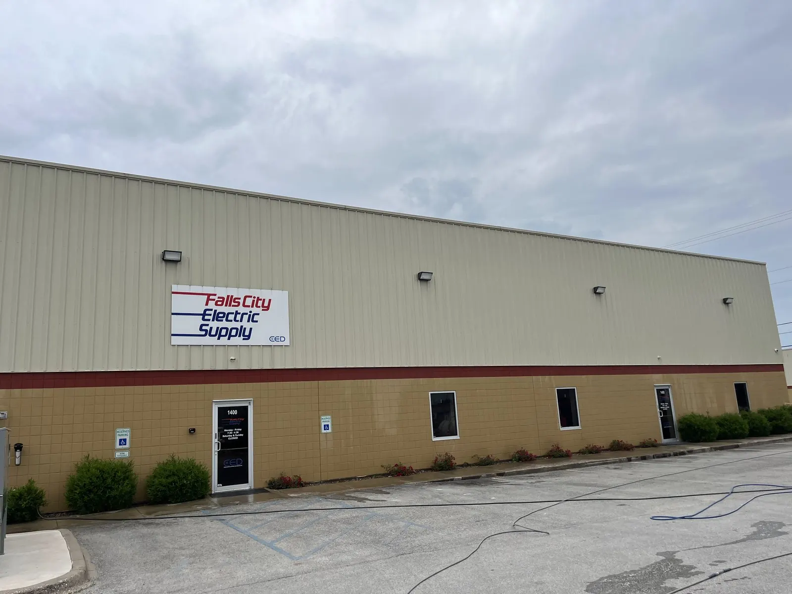 Long metal warehouse with hoses across the parking lot