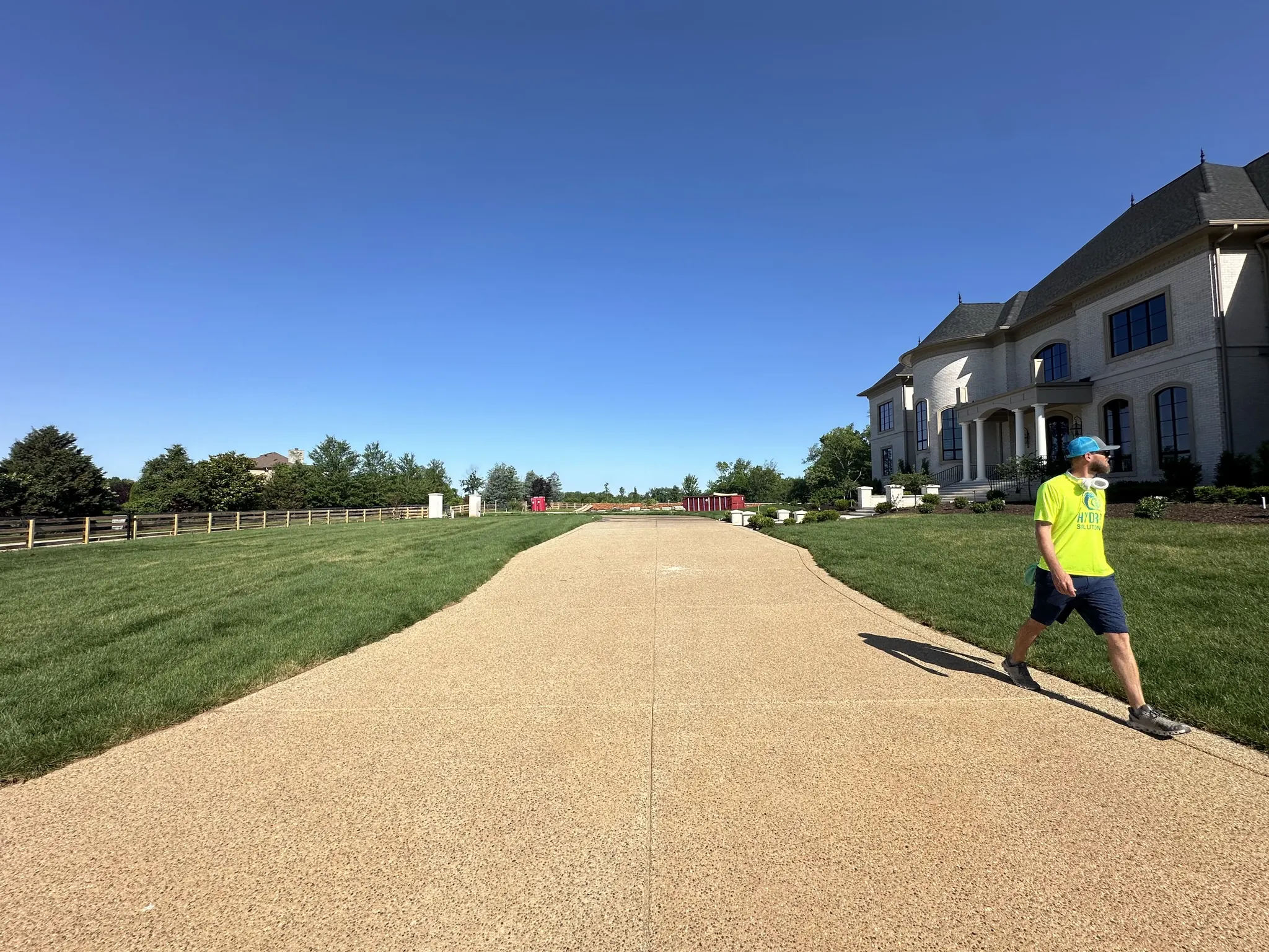 Worker cleaning a long exposed-aggregate concrete driveway