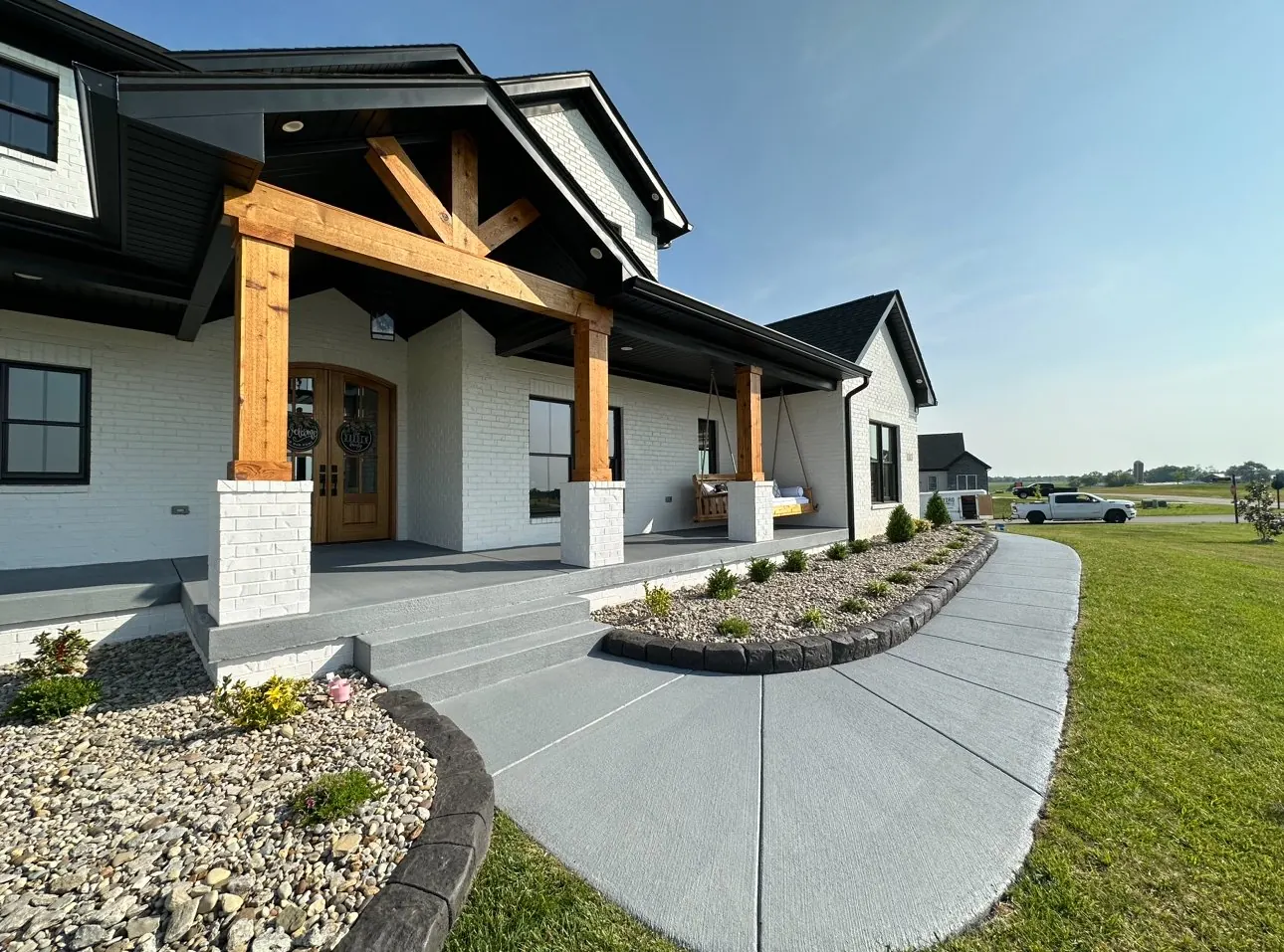 Gray concrete porch, steps and curved walkway in front of a new home