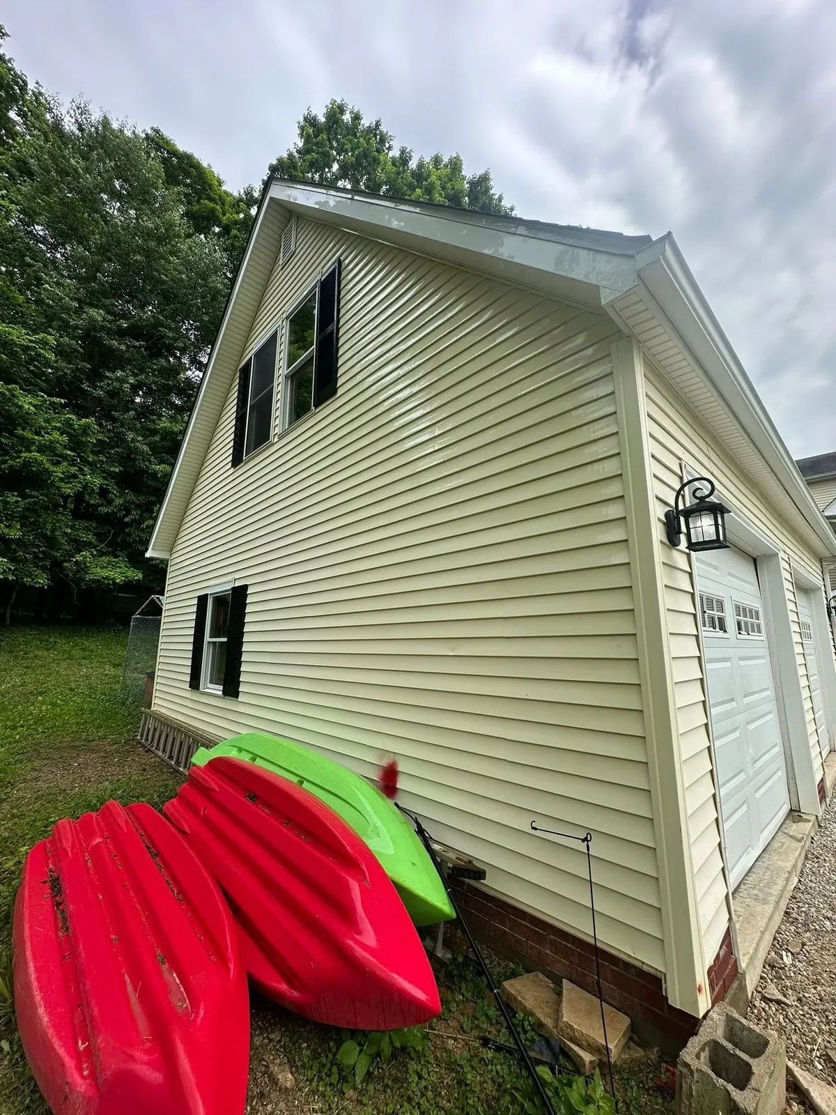 Clean yellow vinyl siding on the side of a house, with kayaks on the lawn