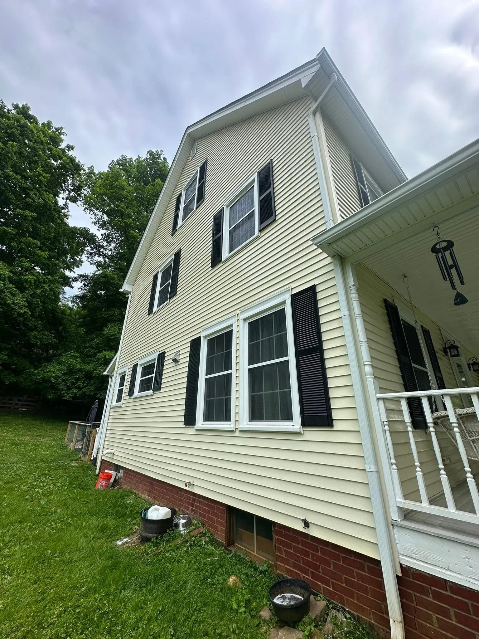 Clean yellow siding along the side of a house after washing