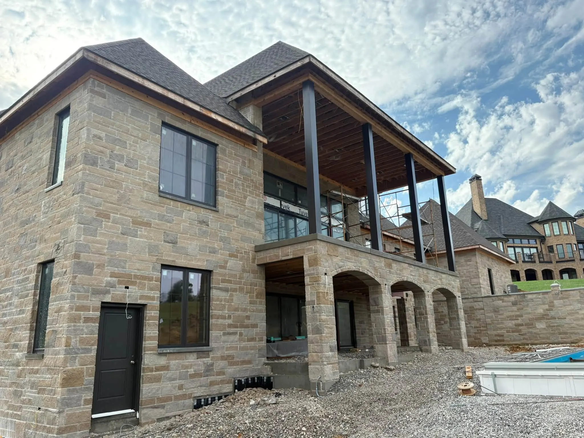 Back of a new stone house with a covered balcony during construction