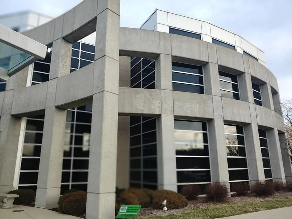 Curved concrete office facade with tall windows and square columns