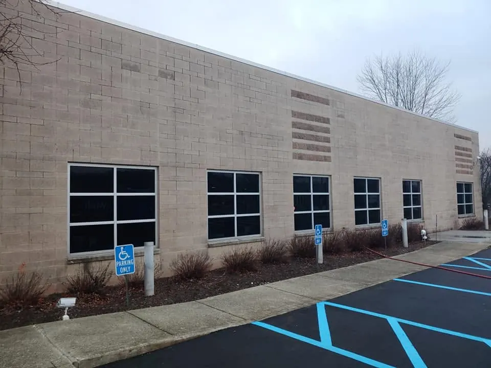 Long tan block wall of a commercial building above a parking lot