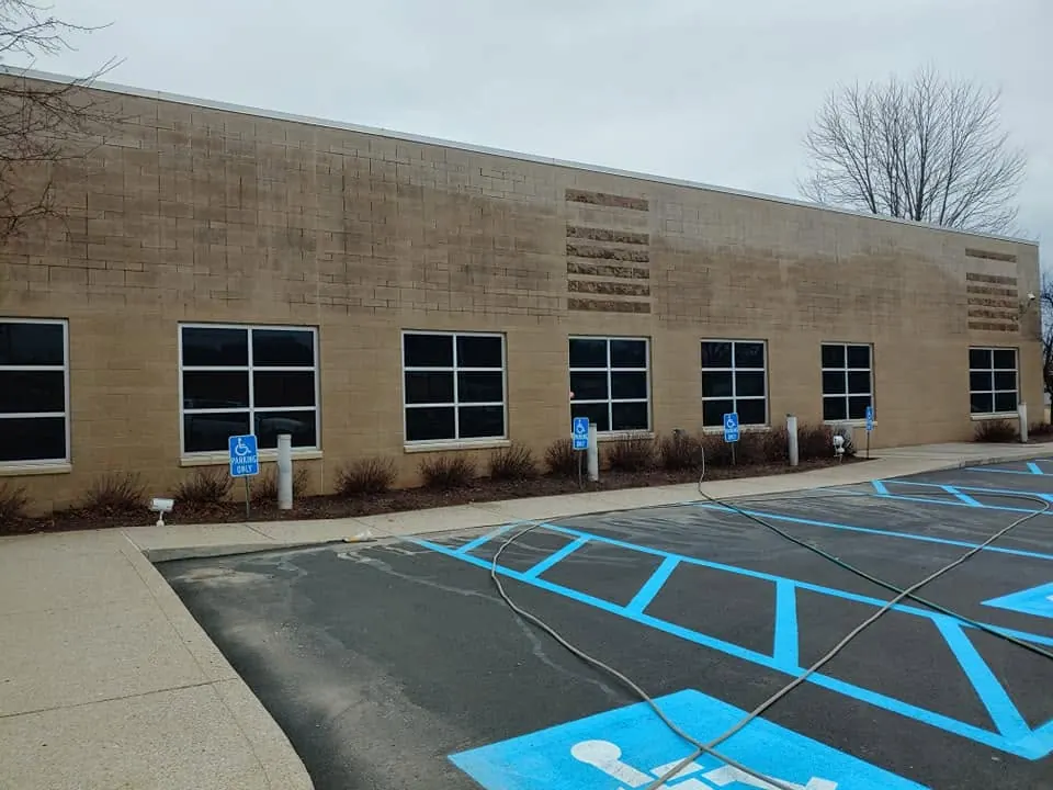 Tan block wall of a commercial building with dark staining below the roofline