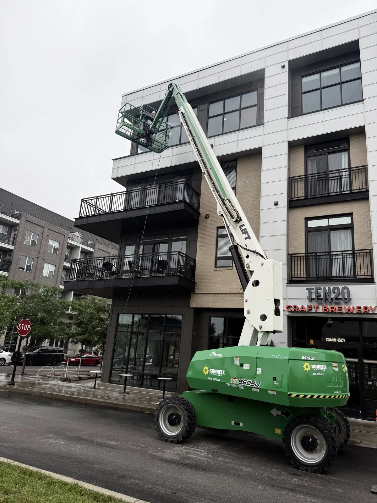 Boom lift beside a modern mixed-use building with balconies