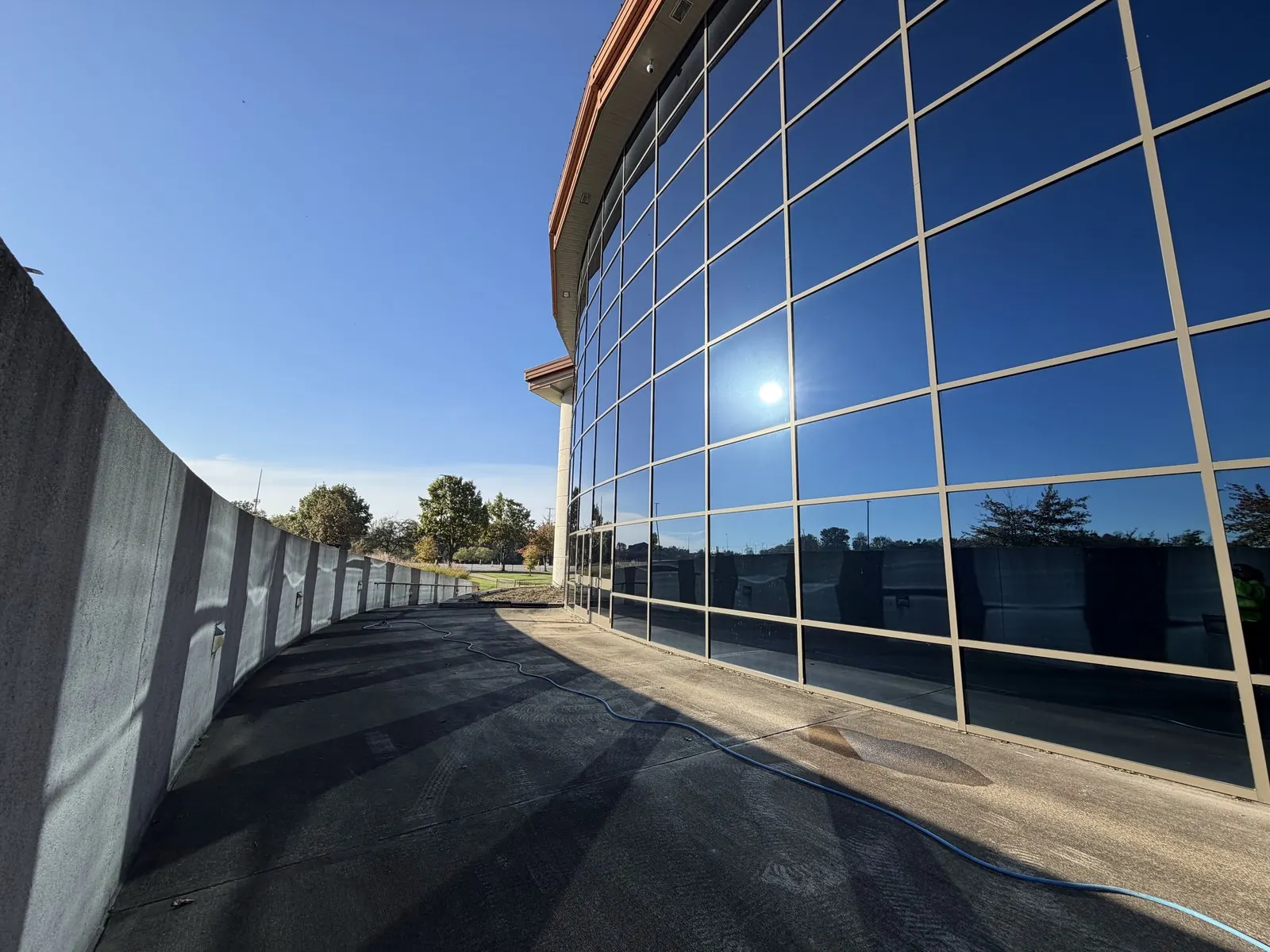 Curved glass curtain wall of a modern building beside a long, wet walkway