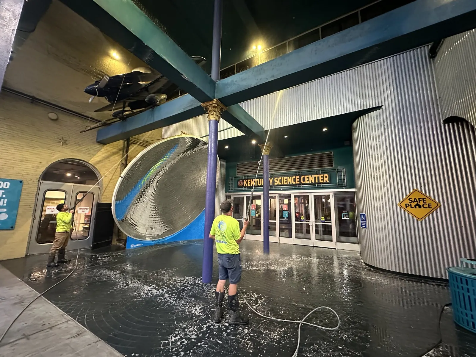 Two workers washing the entrance plaza of a science museum