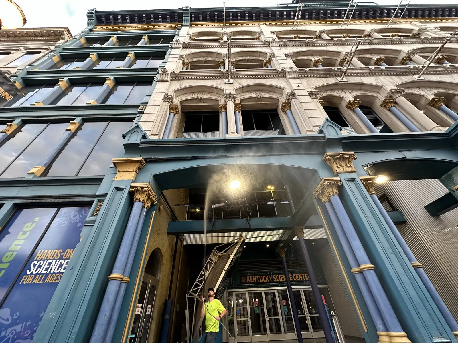 Worker spraying the ornate front of a historic building