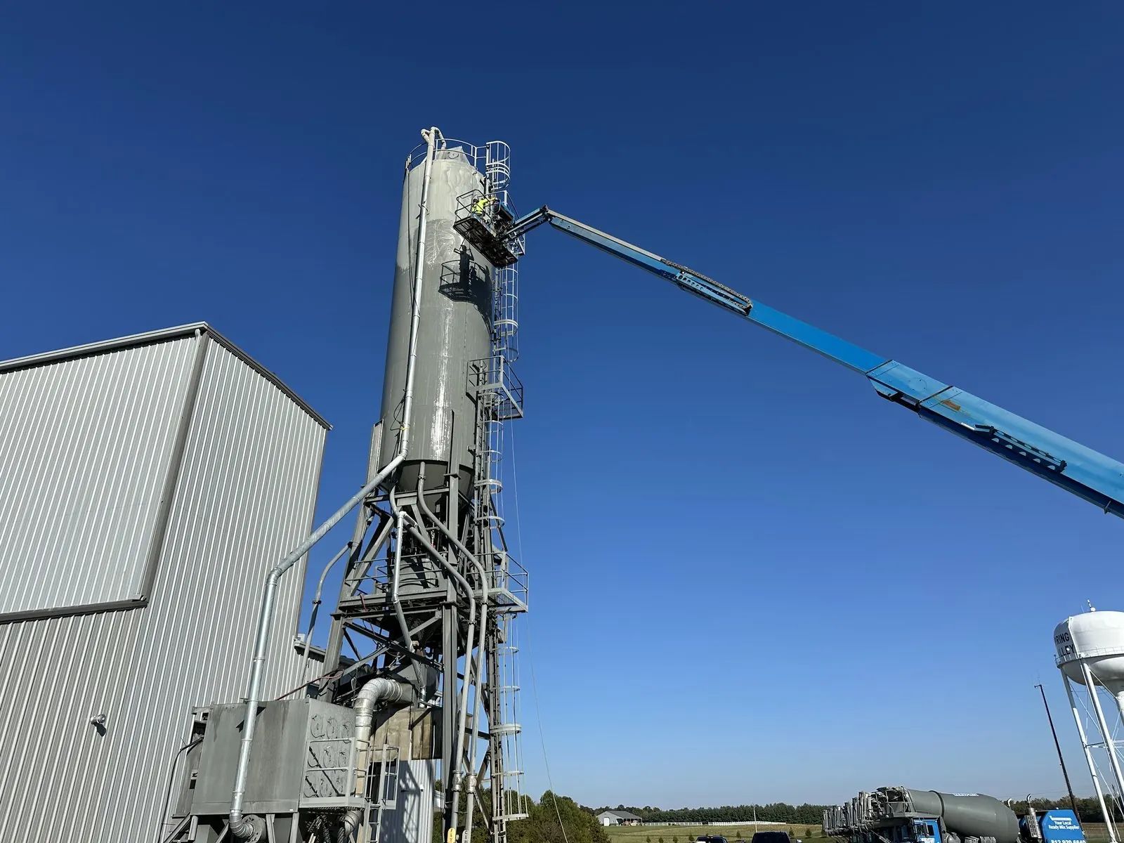 Telescopic boom lift reaching the top of a tall industrial silo