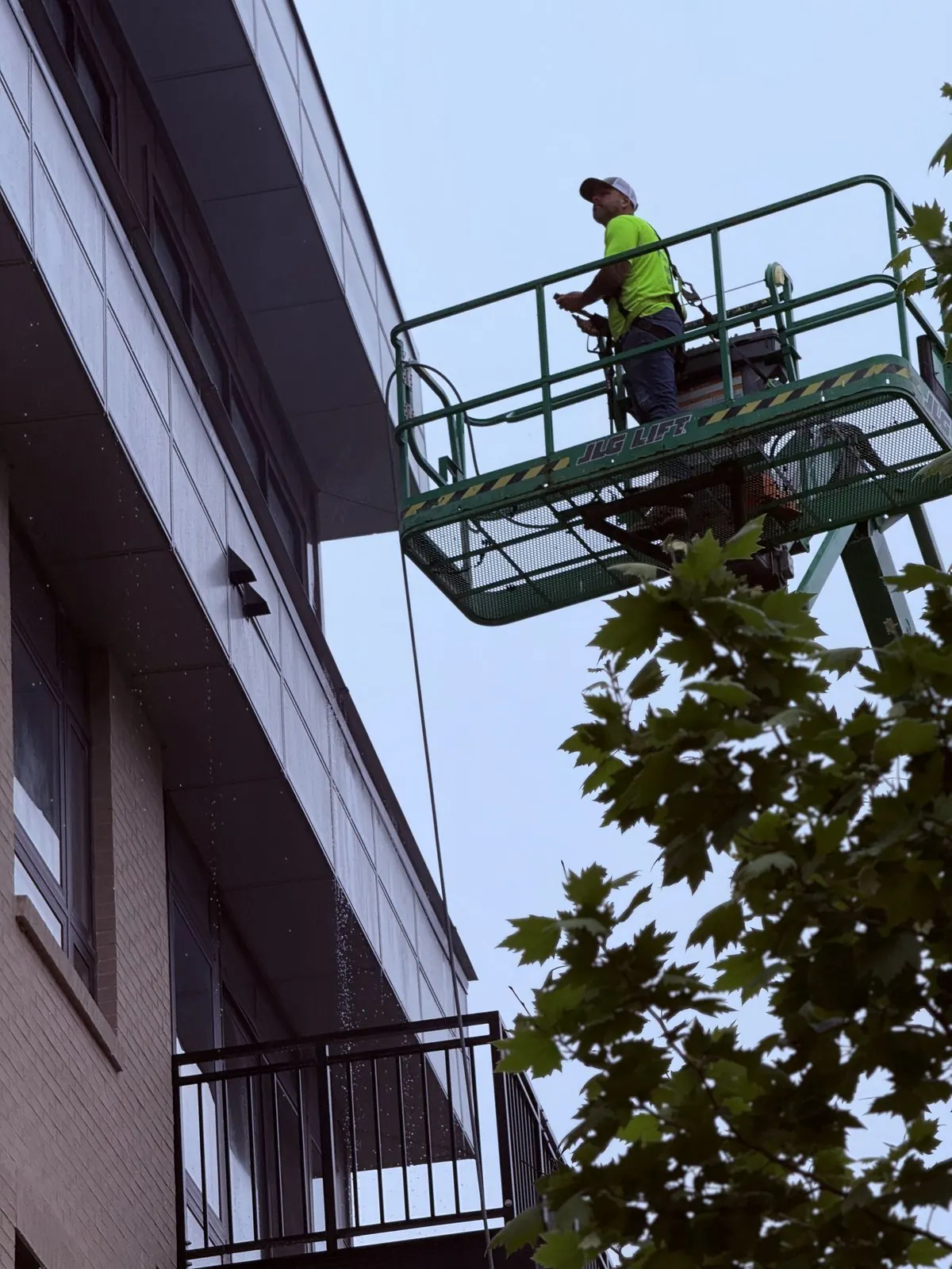 Worker in a lift basket beside a brick building facade