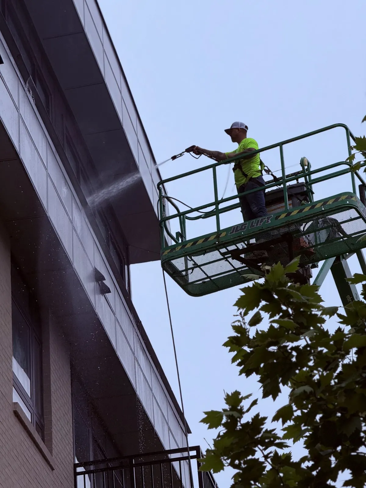 Worker spraying a building facade from a lift basket