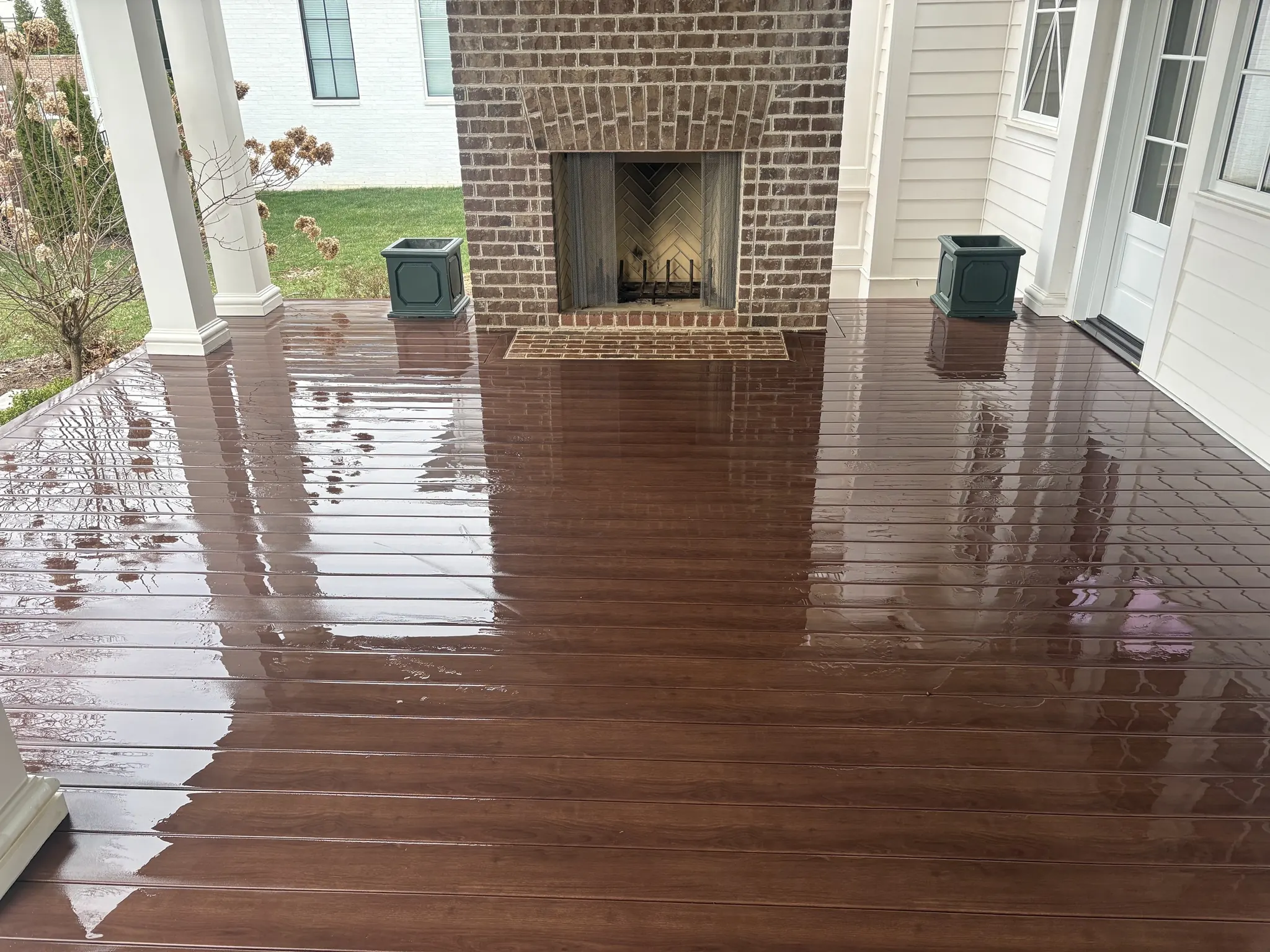 Covered wooden porch deck with a brick outdoor fireplace