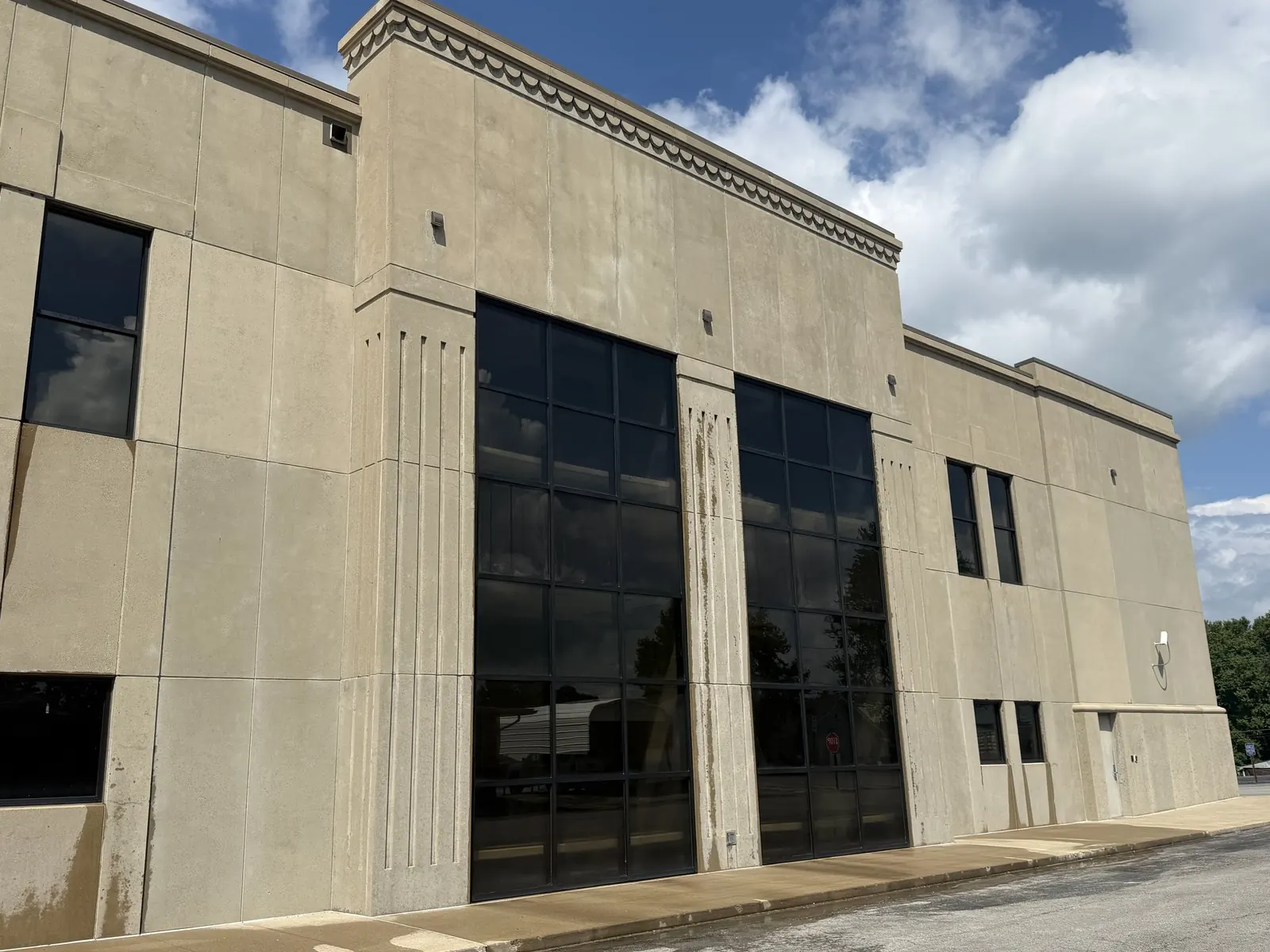 Precast concrete facade of a commercial building with dark streaks below the parapet and windows