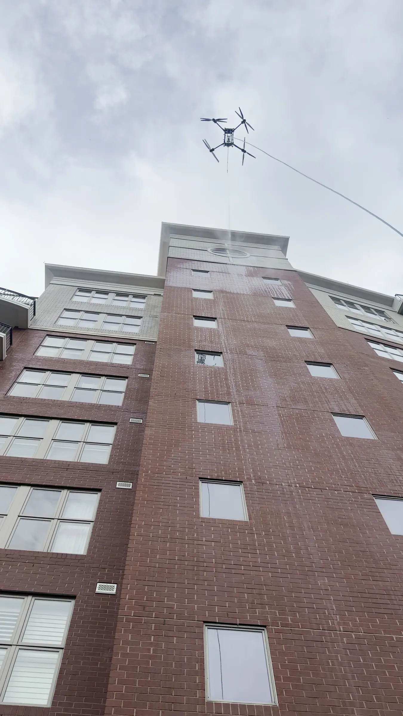 Drone washing a brick high-rise wall